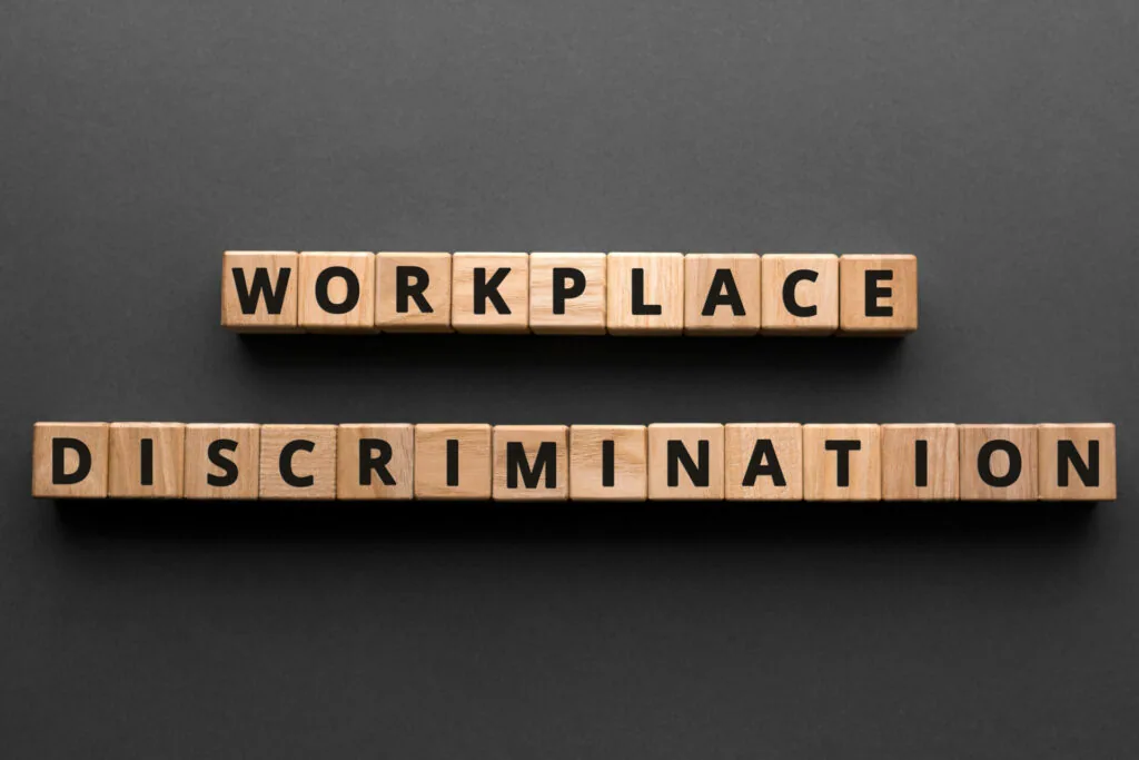 Wooden tiles spelling 'WORKPLACE DISCRIMINATION' on gray background