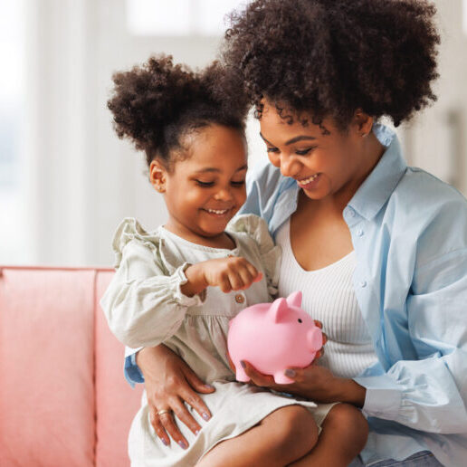 financial education. african american family, mother and child daughter with pig piggy bank counting savings at home on sofa